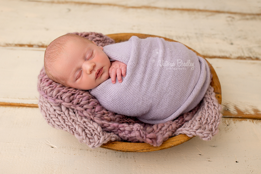 swaddled newborn in purple 