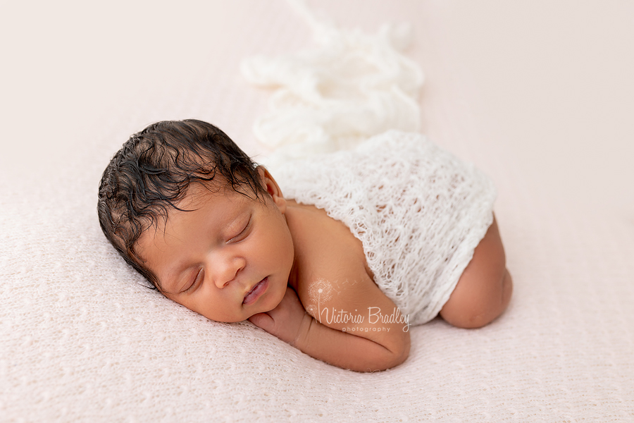 baby on tummy on pink backdrop