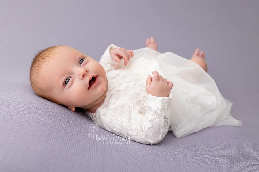 smiling newborn baby girl on purple backdrop photography