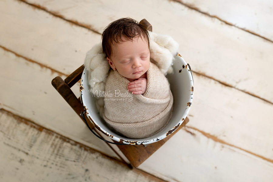 wrapped newborn in bucket on chair