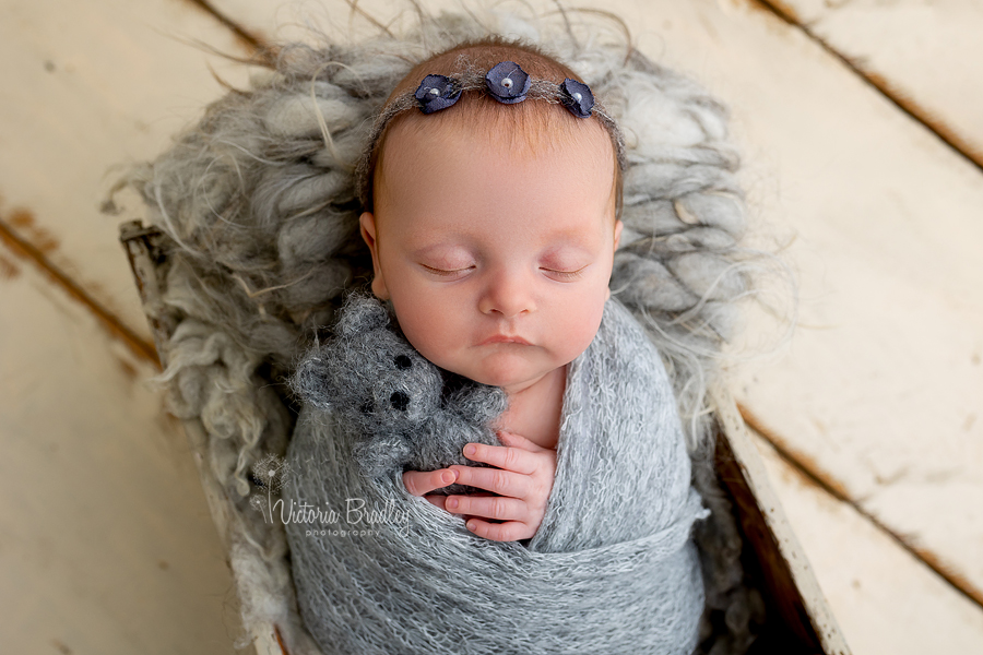 sleepy newborn in grey with small teddy