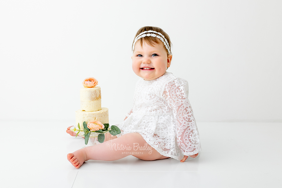 smiling baby girl 1 year cake smash white 