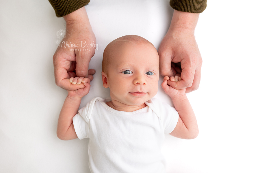 smiling baby boy holding Daddy's hands