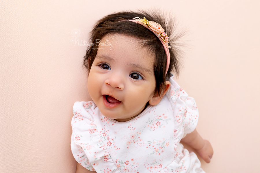 smiling newborn on peach backdrop