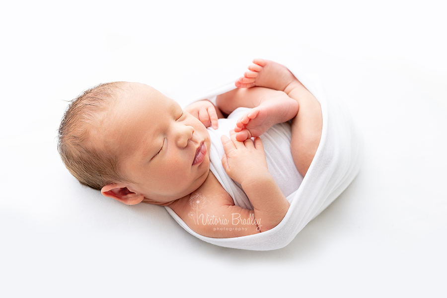 newborn baby boy photography on white backdrop with white wrap