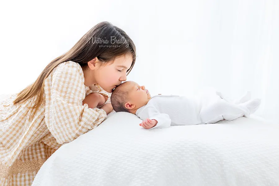 older sibling kissing newborn head