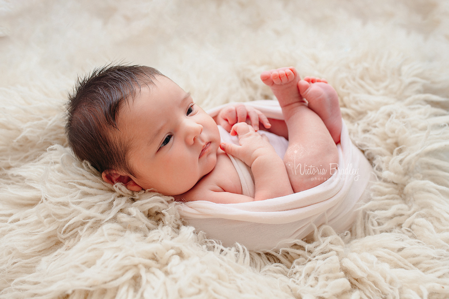 awake newborn on cream flokati rug