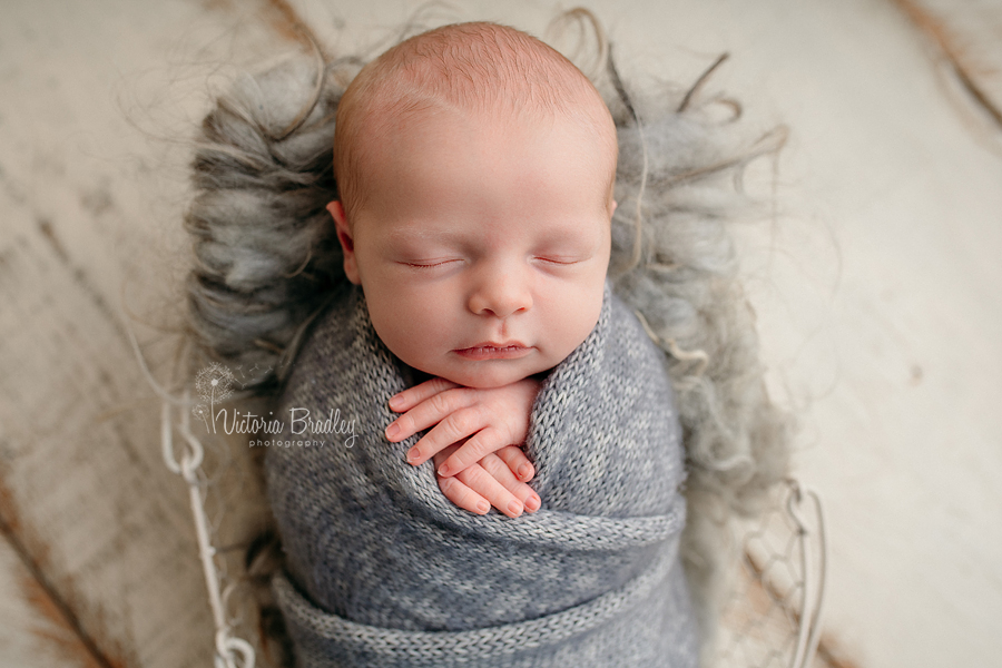 wrapped newborn baby in grey knitted wrap