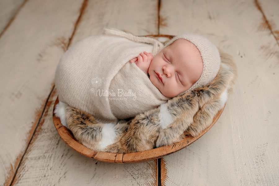 wrapped newborn in wooden bowl