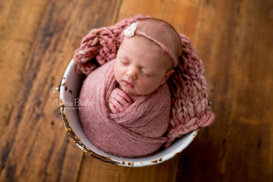 dusky pink wrapped newborn baby in bucket photorgaphy