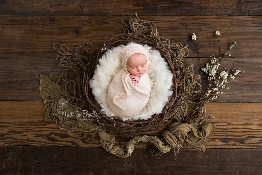 newborn baby in rustic basket on dark wood floor