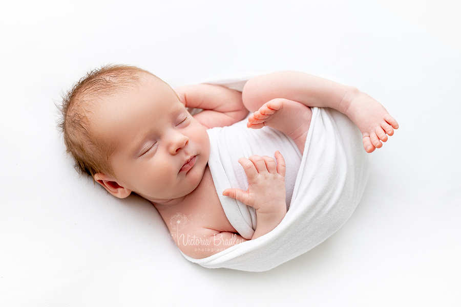 wrapped newborn baby on white backdrop