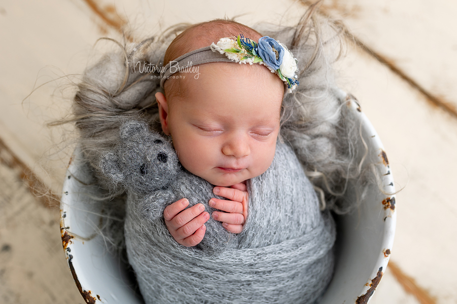 newborn wrapped in grey with grey teddy