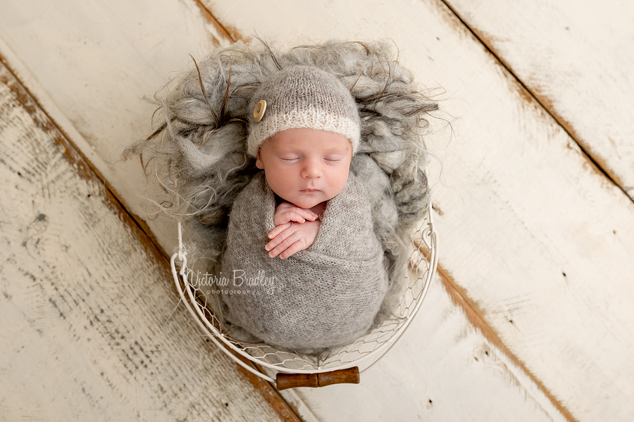 swaddled newborn in grey wrap with beanie hat