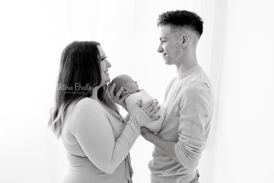 newborn with parents in black and white