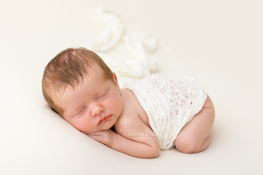 sleepy newborn on tummy on yellow blanket