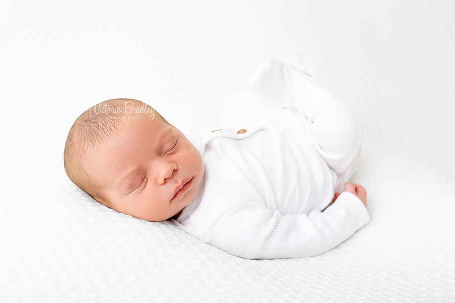 sleepy newborn on white backdrop