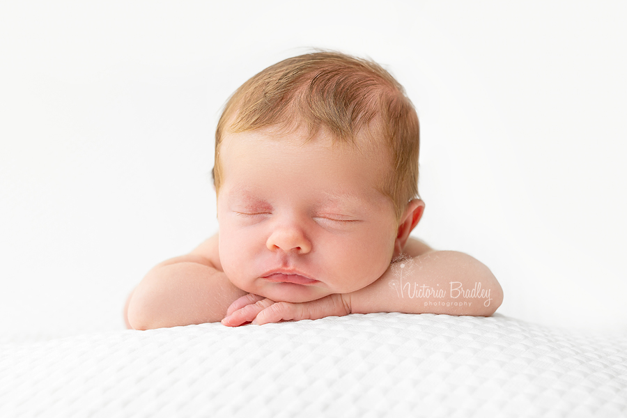 chin on hands pose newborn on white backdrop