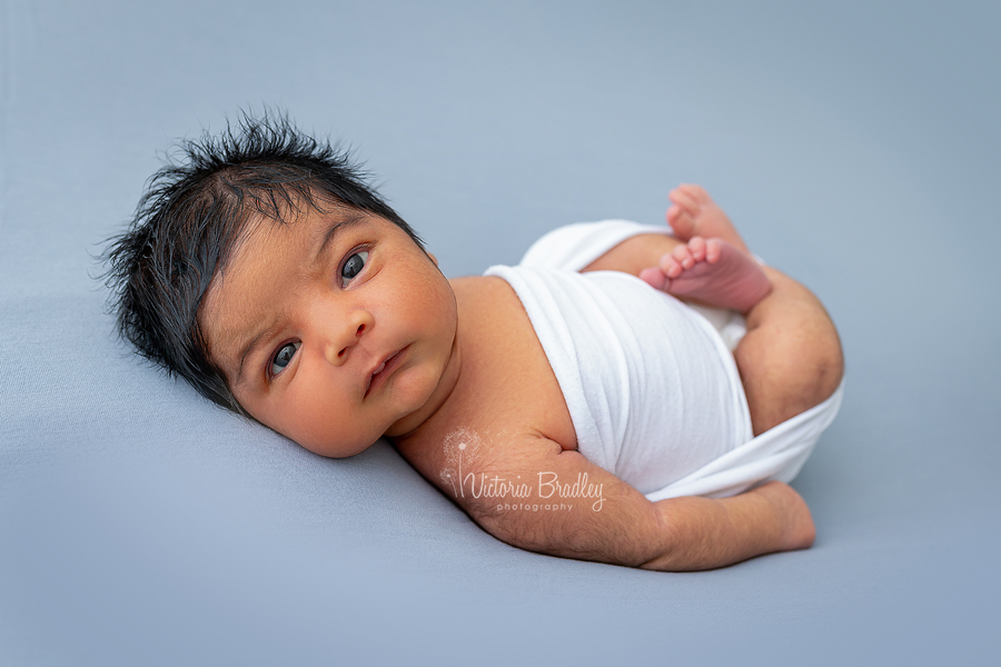 wrapped newborn awake on grey backdrop