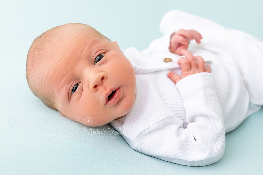 awake newborn on blue backdrop