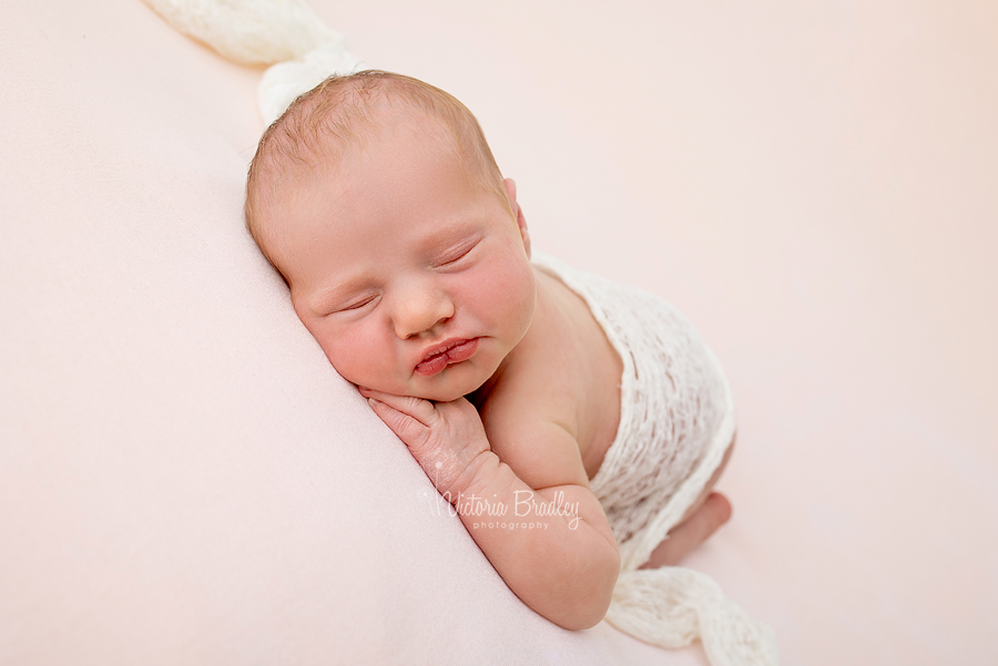 sleepy baby on tummy on pink backdrop