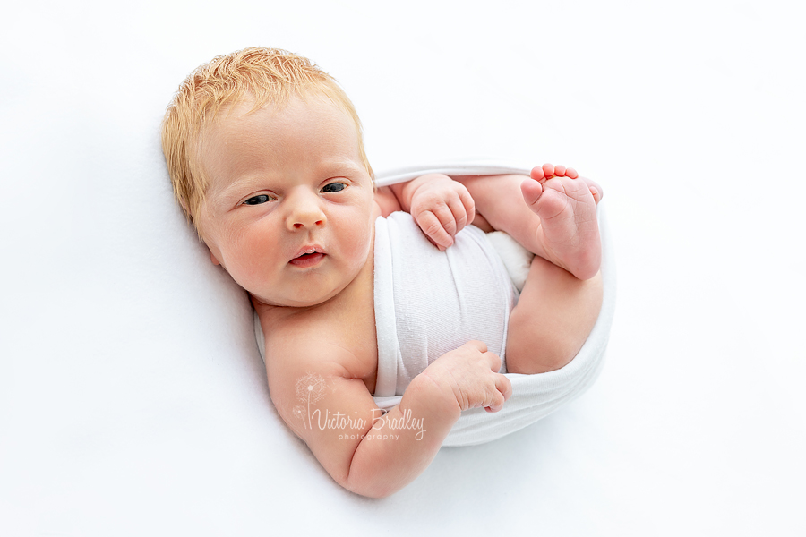 awake newborn on white backdrop